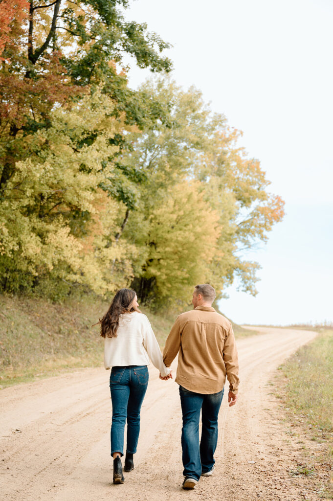 Man and woman walking hand in hand on a dirt road