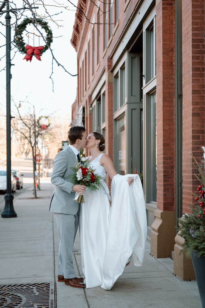 Bride and groom kiss on the sidewalk