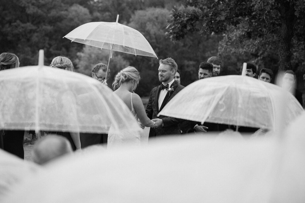 Bride and groom holding hands during rainy ceremony 