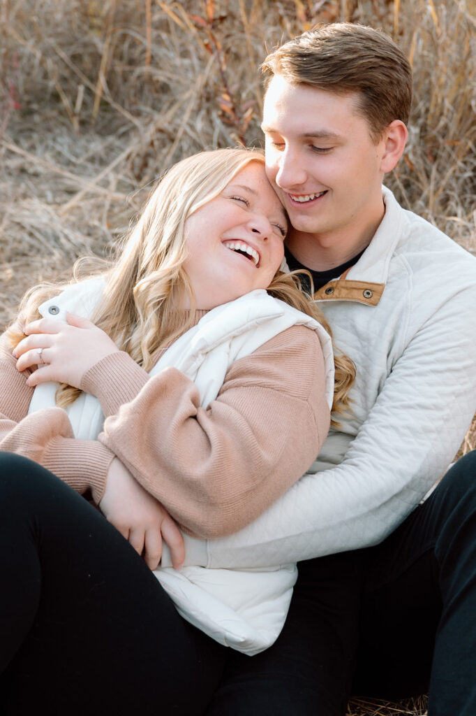 Engaged couple embracing and laughing in a field