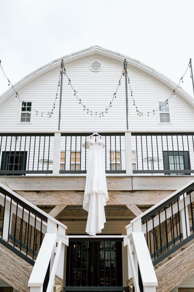 Wedding dress hanging from barn railing