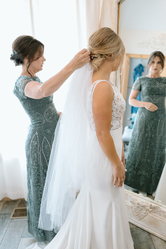 Mom helping daughter put in veil on wedding day